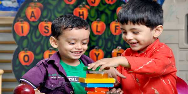 Two Young kids Sitting on the table and playing with building blocks.