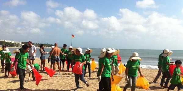 Group of Children standing on the sandy beach and doing some service related activity.