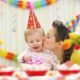 A Happy Mother Kissing Her Cute Smiling Child During Birthday Celebration.